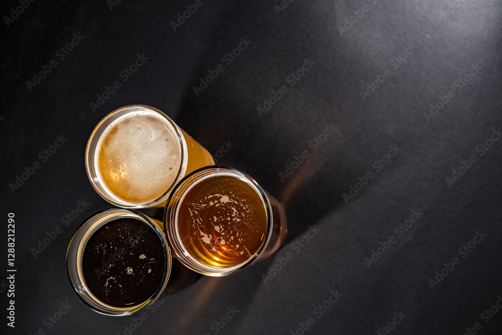 Three glasses of beer in the lower left corner with empty space on the right, top view