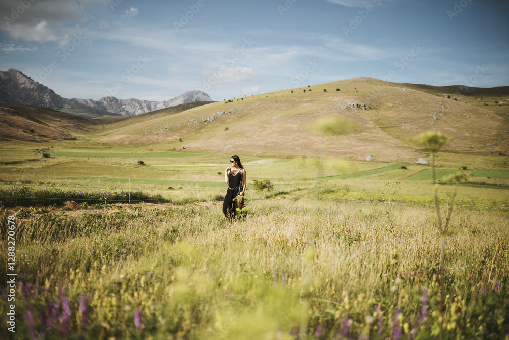 view of beautiful woman in black outfit holding necklace in a beautiful mountains land view of beautiful woman in black outfit holding necklace in a beautiful mountains land