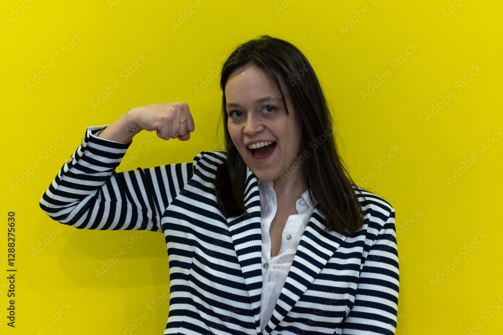 Businesswoman showing her strength and smiling on yellow background Businesswoman showing her strength and smiling on yellow background