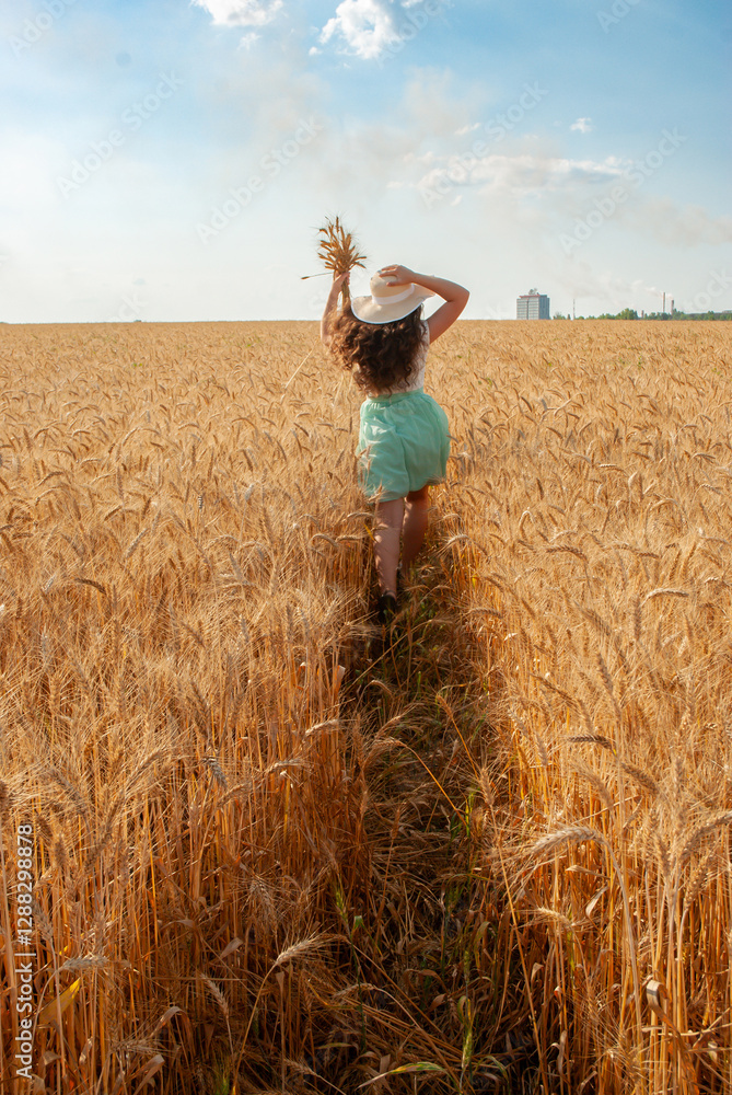 Woman walking through wheat field on a sunny day. Harvesting concept Woman walking through wheat field on a sunny day. Harvesting concept