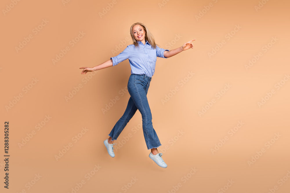 Smiling businesswoman in casual attire joyfully jumping on a beige background in a cheerful and stylish pose Smiling businesswoman in casual attire joyfully jumping on a beige background in a cheerful and stylish pose