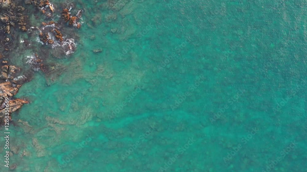 An aerial view of a rocky coastline with clear turquoise water. Sunlight reveals underwater rock formations and reefs, creating a stunning tropical seascape. An aerial view of a rocky coastline with clear turquoise water. Sunlight reveals underwater rock formations and reefs, creating a stunning tropical seascape.