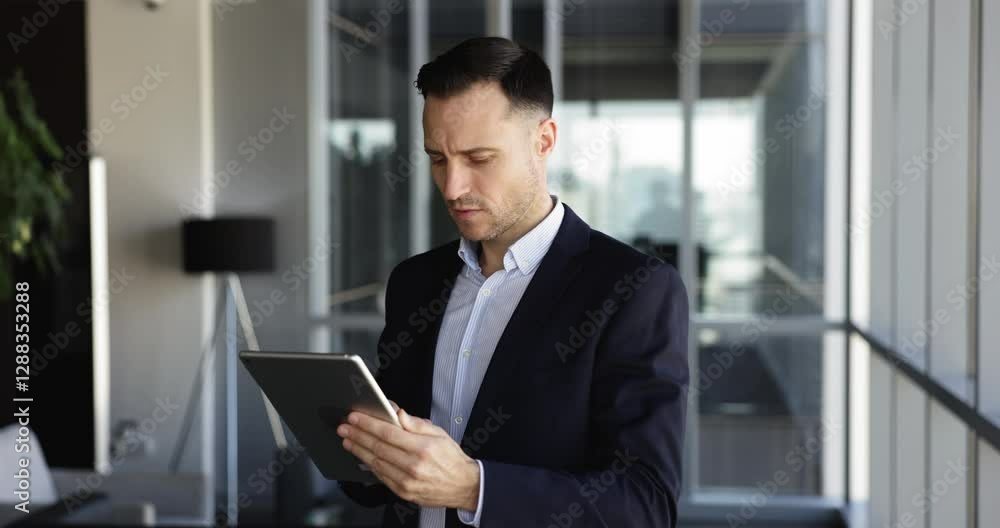 Serious thoughtful Latin business leader man using financial online service on tablet, making payment, transaction, analyzing investment, typing on gadget in office, looking away, touching chin Serious thoughtful Latin business leader man using financial online service on tablet, making payment, transaction, analyzing investment, typing on gadget in office, looking away, touching chin