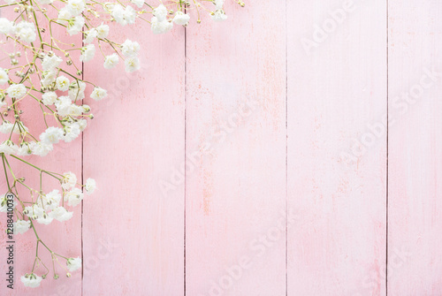 Tiny white flowers of Gypsophila  on a light pink shabby wooden background. Top view with copy space. Flat lay.