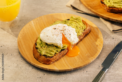 avocado toast with a poached egg on top, on a bamboo plate