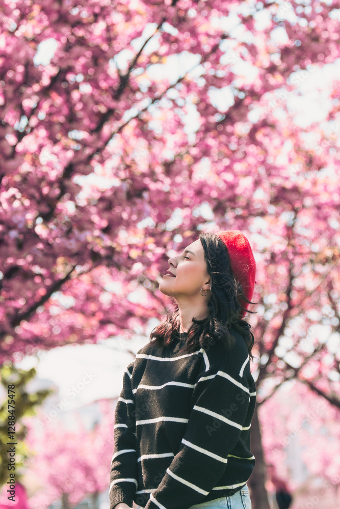 pretty smiling woman posing in front of blooming sakura trees