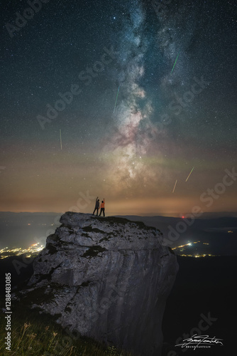silhouette of a couple standing on a rock and watching perseid meteor shower