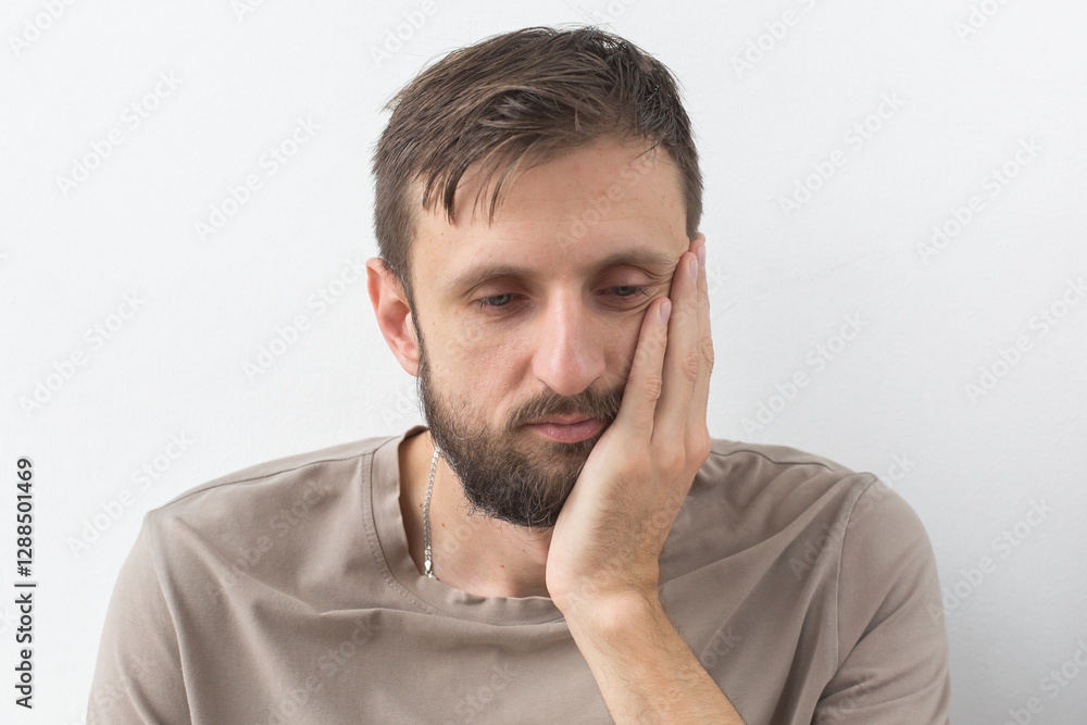 Man holding his cheek with a pained expression, indicating toothache, dental discomfort, or oral health issues, highlighting the need for dental care and treatment concept Man holding his cheek with a pained expression, indicating toothache, dental discomfort, or oral health issues, highlighting the need for dental care and treatment concept