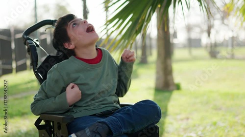 Disabled child looking up in wheelchair in park photo