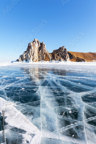 Wallpaper Mural Scenic winter landscape of frozen Baikal Lake. View of famous Shamanka Rock - natural landmark of Olkhon Islands from blue clear ice with cracks on sunny day of February. Winter travels and recreation Torontodigital.ca