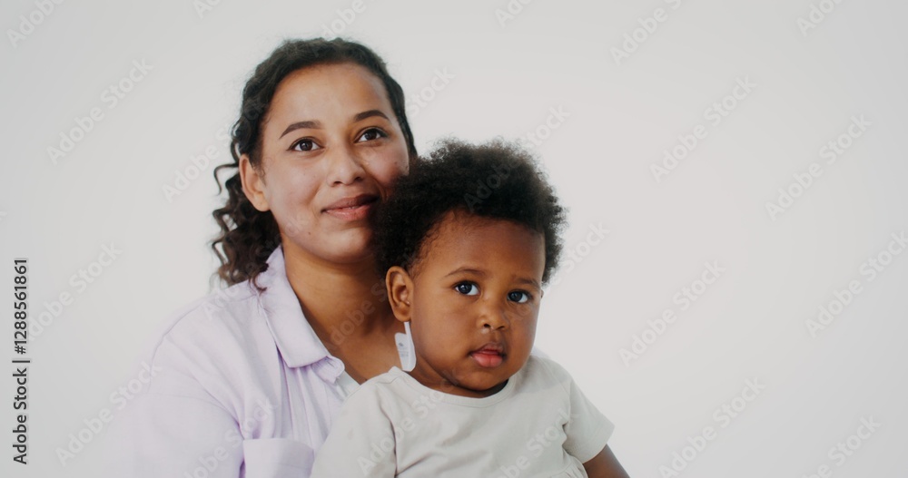 Mom and daughter of African-American appearance smile while looking at the camera posing on a white studio background Mom and daughter of African-American appearance smile while looking at the camera posing on a white studio background