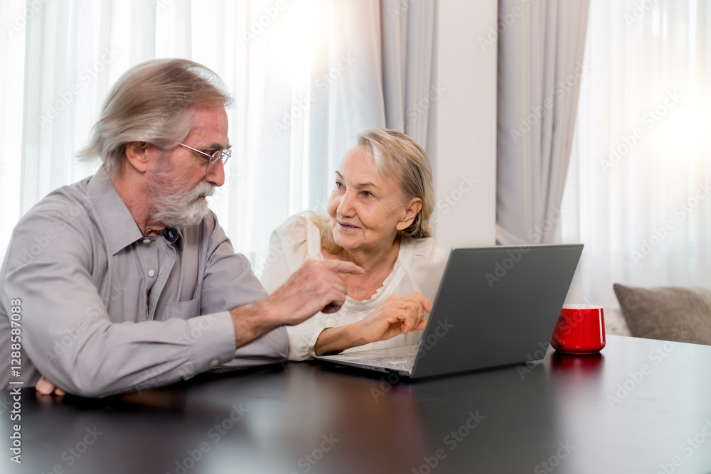 Obraz premium Happy Caucasian 70s mature couple using laptop at home. Old people using computer at home. Senior man and woman surfing the web on a wireless laptop connection. Modern retired lifestyle people.