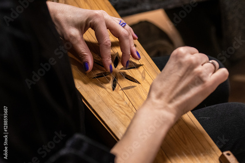 Fingers of a girl playing kankles, Lithuanian plucked string instrument belonging to the Baltic box zither family known as the Baltic psaltery, in Latvian kokles, Estonian kannel, Finnish kantele photo