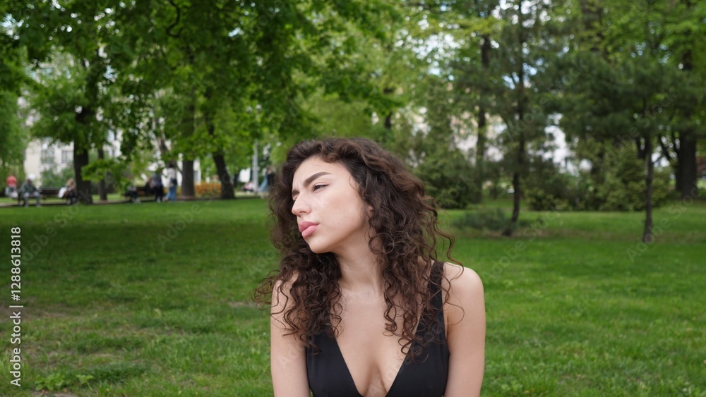 A captivating and charming woman with beautiful curly hair gracefully poses in a serene, relaxing park setting A captivating and charming woman with beautiful curly hair gracefully poses in a serene, relaxing park setting