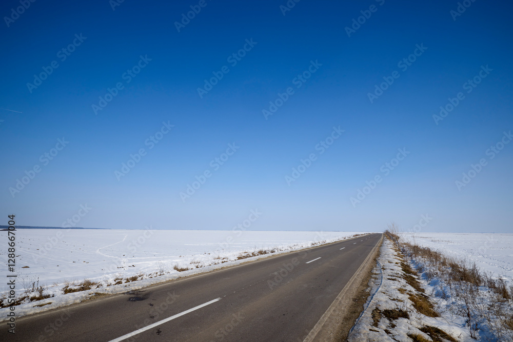asphalt road on a snow-covered agricultural field asphalt road on a snow-covered agricultural field