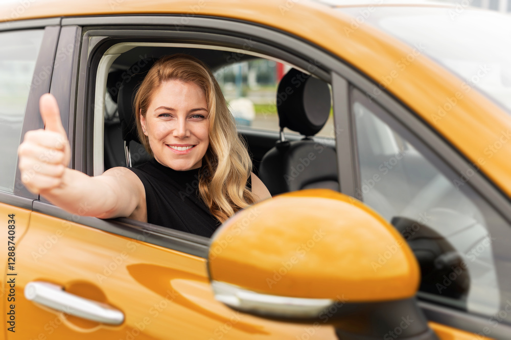 A confident blonde woman sits in a yellow car, smiling and giving a thumbs-up through the window, symbolizing success, happiness, and independence.