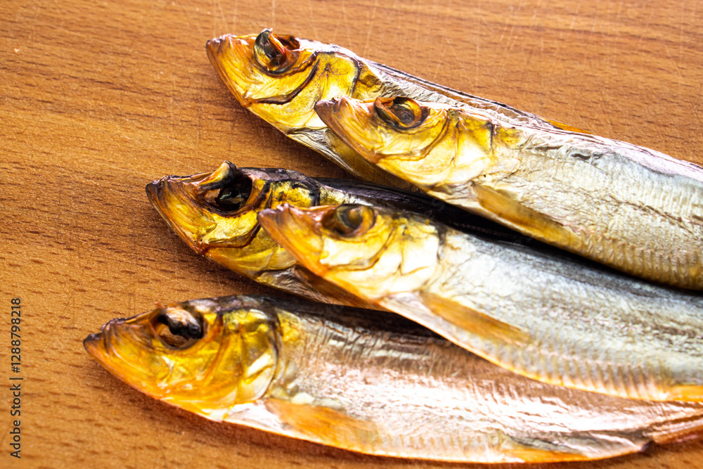 Hot smoked whole herrings on kitchen table. smoked fish isolated on a wooden background Hot smoked whole herrings on kitchen table. smoked fish isolated on a wooden background