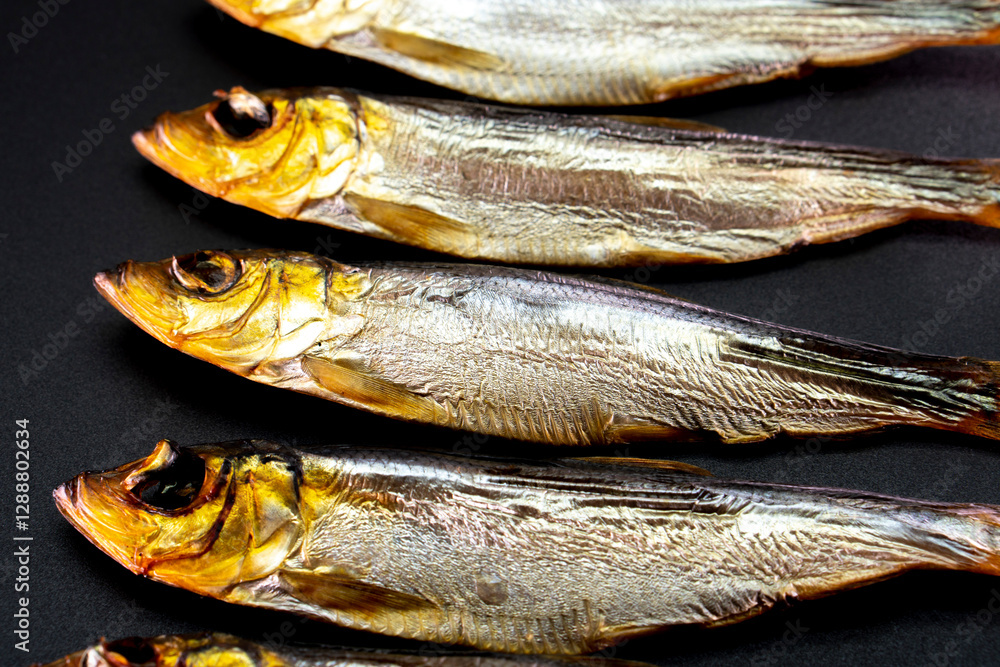 Hot smoked whole herrings on kitchen table. smoked fish isolated on a black background Hot smoked whole herrings on kitchen table. smoked fish isolated on a black background