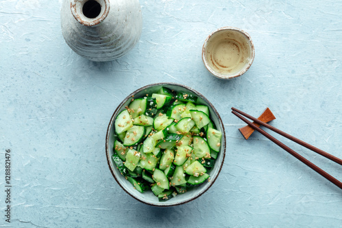 Smashed cucumber salad, healthy vegan food, green plant-based appetizer, overhead flat lay shot with sake and chopsticks photo