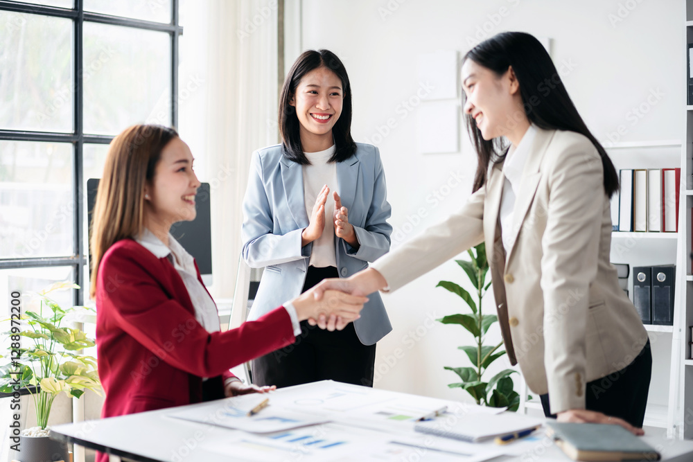 Three women are shaking hands in a business setting Three women are shaking hands in a business setting