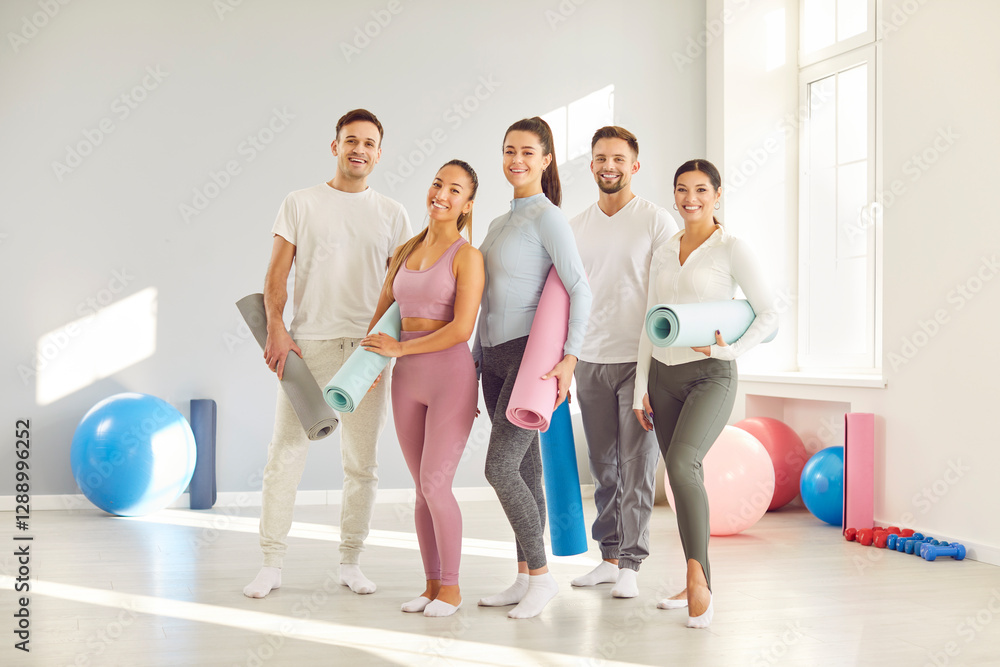 Fototapeta premium Group of young sporty happy people posing, fitness club sportswomen team holding yoga mats. Active friends before, after exercise or sport instruction, recreational activity together, balance work