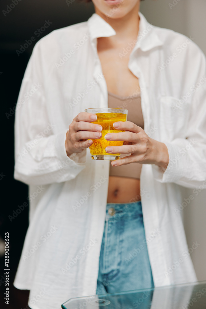 Woman holding a glass of orange juice and a cup of coffee on a table with a glass of water Woman holding a glass of orange juice and a cup of coffee on a table with a glass of water