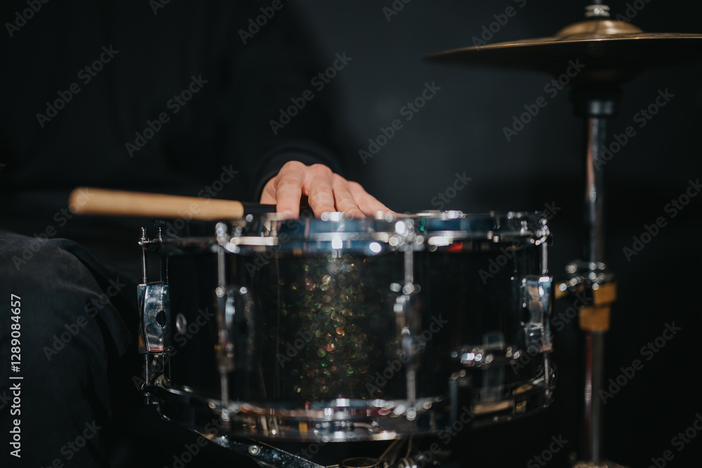 A musician's hand resting on a shiny snare drum with drumsticks nearby, emphasizing music and rhythm. A musician's hand resting on a shiny snare drum with drumsticks nearby, emphasizing music and rhythm.