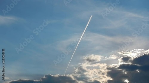 Wallpaper Mural Blue sky, sunlight, flying plane with white streak from condensation cloud from airplane and slowly moving white and grey clouds on horizon. Topics: air travel, transport, sky space, vacation Torontodigital.ca