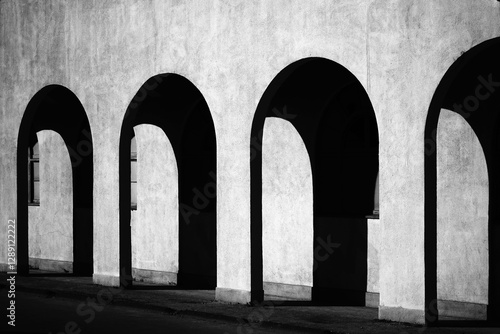 Liminal space black and white Fine art architectural photography showing repeating pattern of light and shadows through the arched exterior hallway of a classic building in the American west.