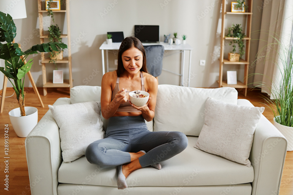 Healthy lifestyle concept with fit sportswoman eating cereals for breakfast in her living room Healthy lifestyle concept with fit sportswoman eating cereals for breakfast in her living room