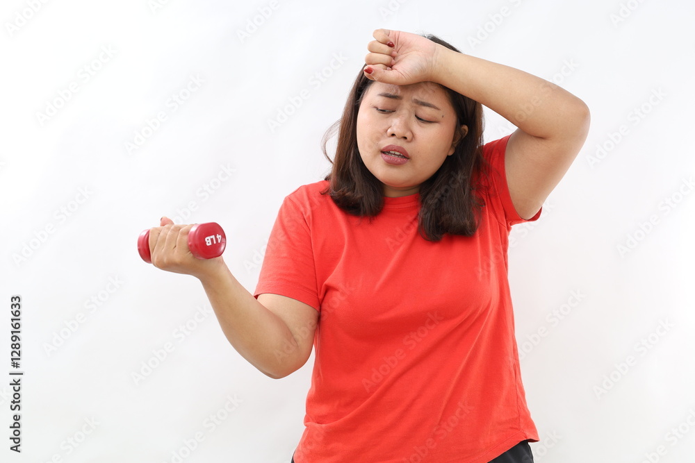 Woman lifting dumbbell while wiping sweat from head, looks tired Woman lifting dumbbell while wiping sweat from head, looks tired
