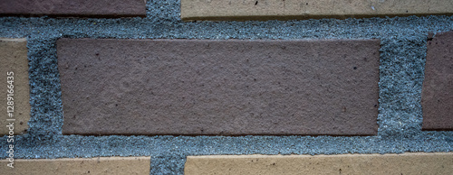 A brick wall with a blue brick in the middle photo