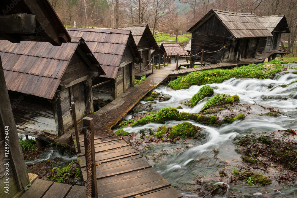 Small wooden water mills on poles on Pliva river near Jajce during overcast day Small wooden water mills on poles on Pliva river near Jajce during overcast day