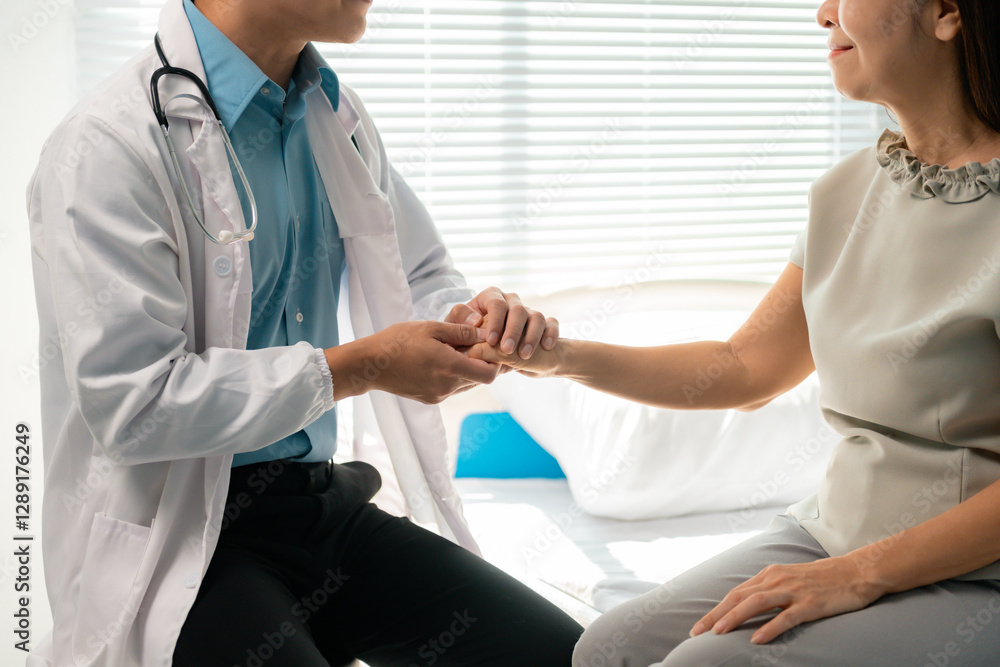 Fototapeta premium Compassionate young physician gently holding hand of senior patient, offering emotional support near sunlit hospital window with caring, empathetic gesture