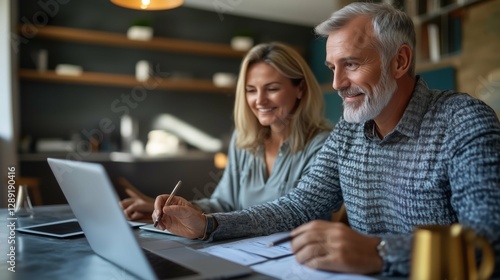 Mature couple reviewing documents and laptop at home, planning finances.