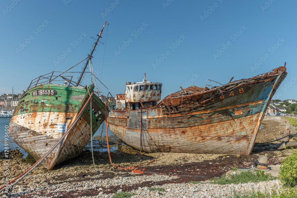 A rusty boat is sitting on the shore next to a large concrete post A rusty boat is sitting on the shore next to a large concrete post