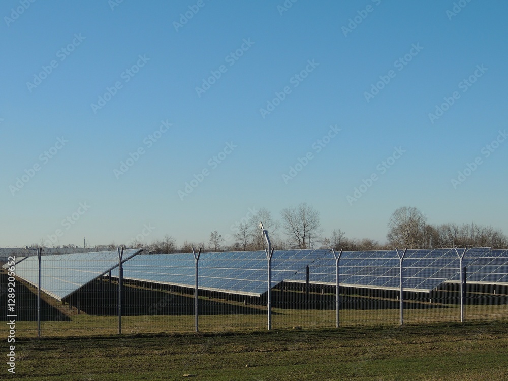 Rows of solar panels in a fenced area under a clear blue sky at a solar power plant outside the city, collecting and accumulating solar energy on an industrial scale