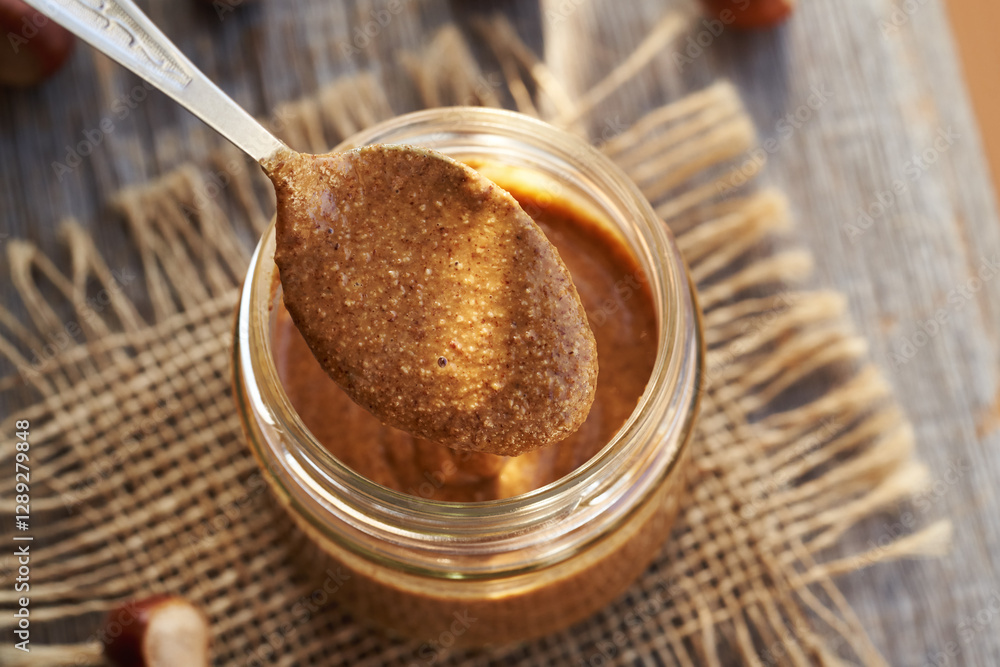 Homemade hazelnut butter on a metal spoon above a glass jar Homemade hazelnut butter on a metal spoon above a glass jar
