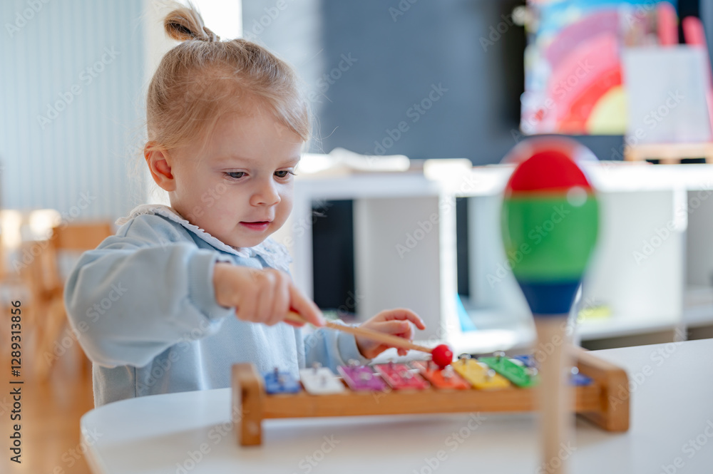 Fototapeta premium A young child plays with a colorful xylophone in a bright and inviting playroom, engaging in musical exploration and sensory learning