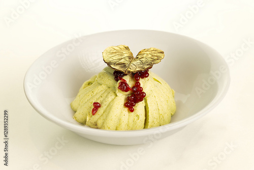 Dessert, muse with one golden leaf on top, and some fruite pulp splashing in the middle