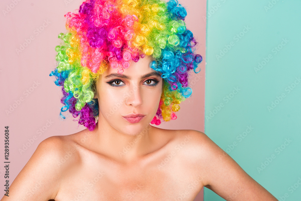 Naklejka premium Young woman in rainbow lgbtq flag wig looking positive and happy. Funny Girl smile. Young transgender woman in wig. Funny woman face. Portrait of attractive funny girl grimacing. Emotion girl.