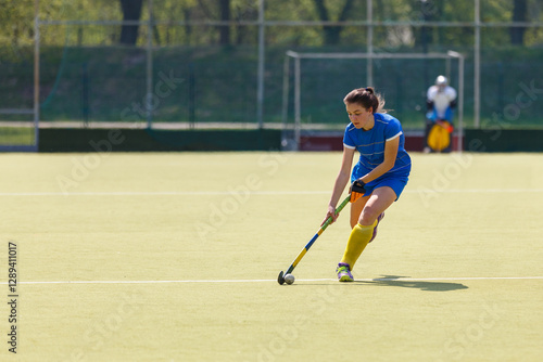 Young field hockey female player leading the ball in attack during the game