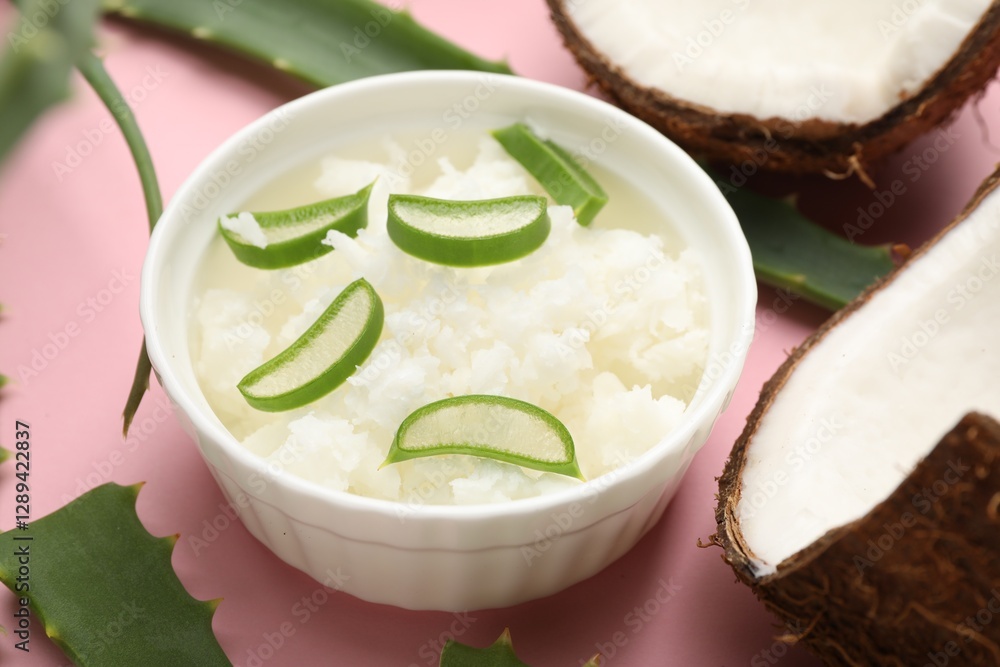 Hair treatment. Coconut butter with aloe leaves on pink background, closeup Hair treatment. Coconut butter with aloe leaves on pink background, closeup