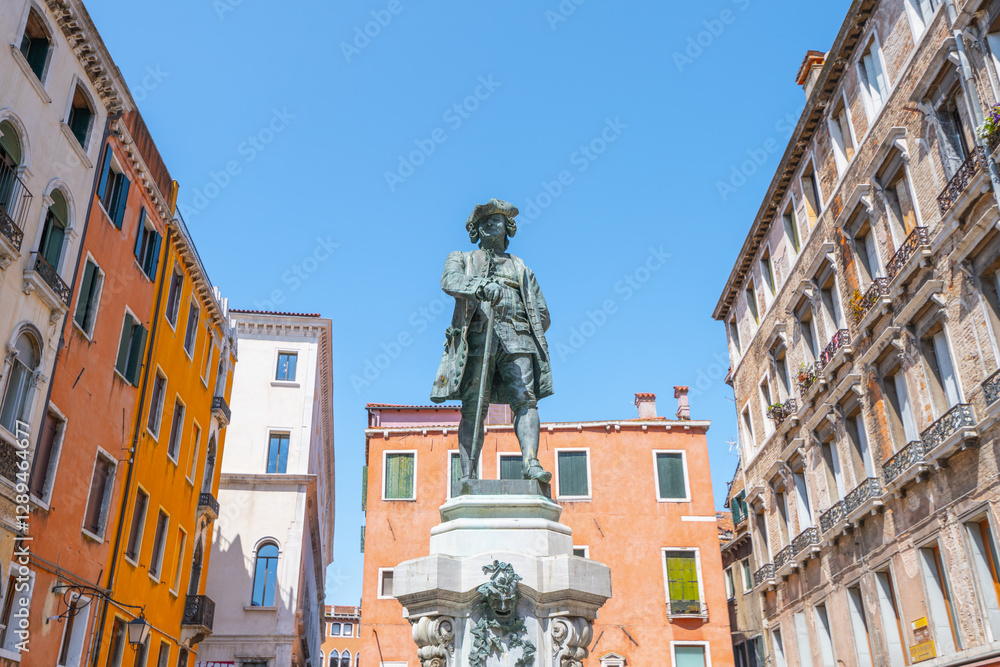 Φωτογραφία A statue of Carlo Goldoni stands proudly in a Venetian square, surrounded by charming buildings under a clear blue sky, capturing the essence of the city's rich cultural heritage
