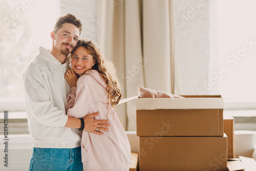 Happy young family couple man and woman hugging after moving cardboard boxes to their new apartment.