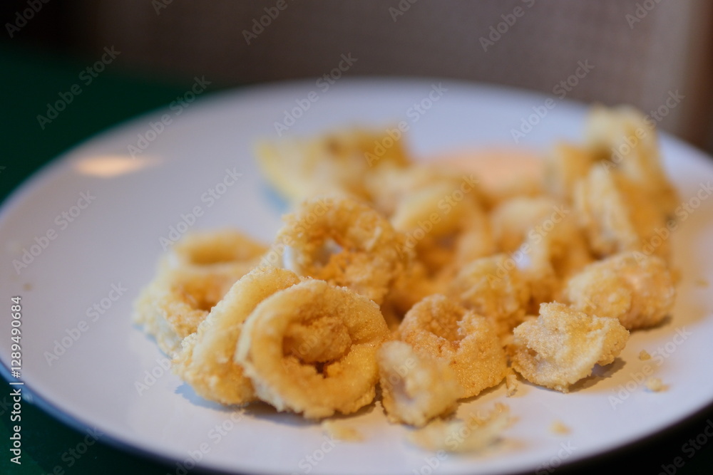 Crispy fried calamari rings on a plate with slices of lemon and parsley on a wooden boards background. High quality photo Crispy fried calamari rings on a plate with slices of lemon and parsley on a wooden boards background. High quality photo