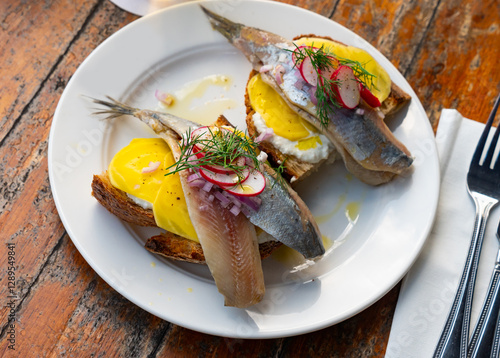 Dutch soused herring served on pieces of bread with radish and yoghurt. photo