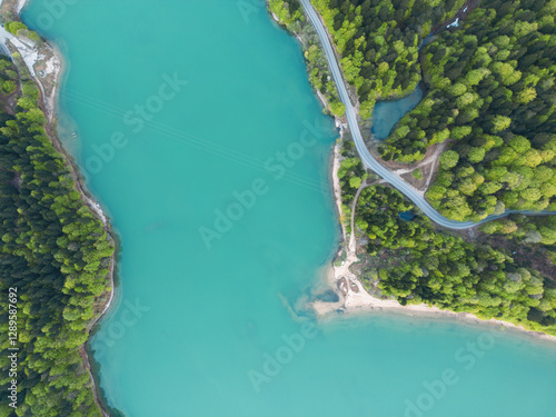 car drives along a road along a mountain lake, forest and sandy cape,aerial view