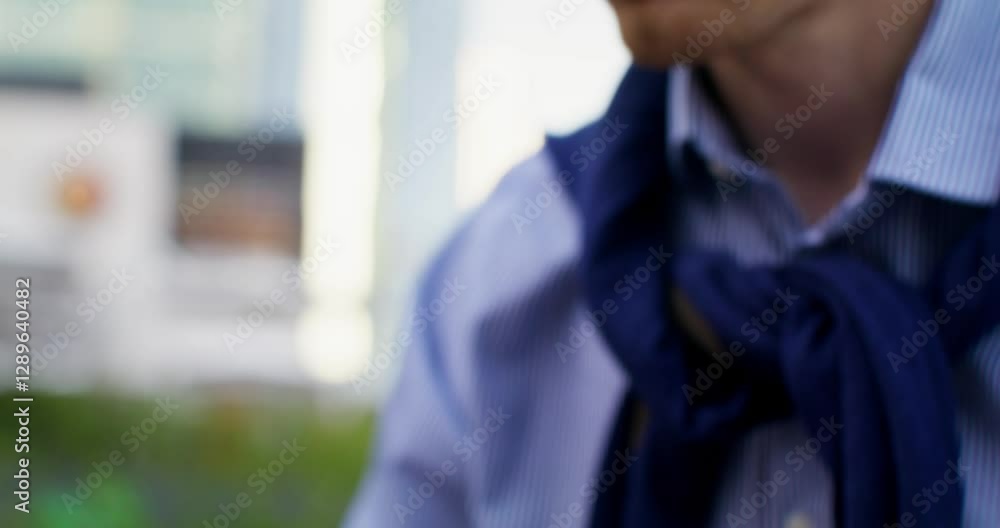 A respectable, serious man is intently using a laptop while sitting outdoors. Headphones on his head A respectable, serious man is intently using a laptop while sitting outdoors. Headphones on his head