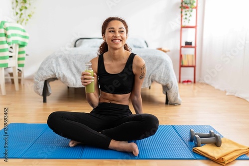 Фотография Young Latin American woman enjoying a refreshing detox juice in her bedroom afte